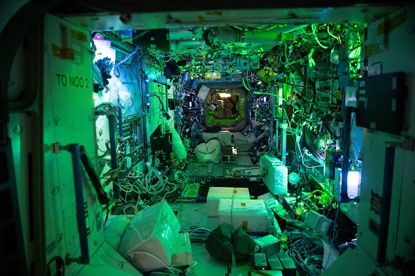 image of the Destiny laboratory with a greenish glow from hardware lighting in the space station at night