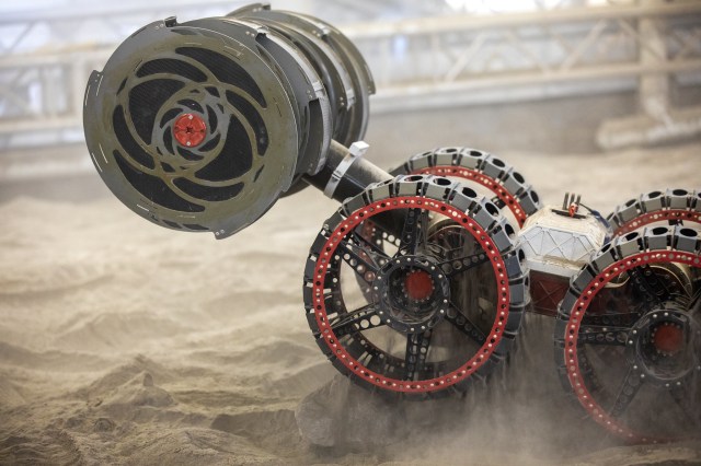 The ISRU Pilot Excavator (IPEx) breadboard unit, also known as RASSOR, digs in the regolith bin during testing inside Swamp Works at Kennedy Space Center.