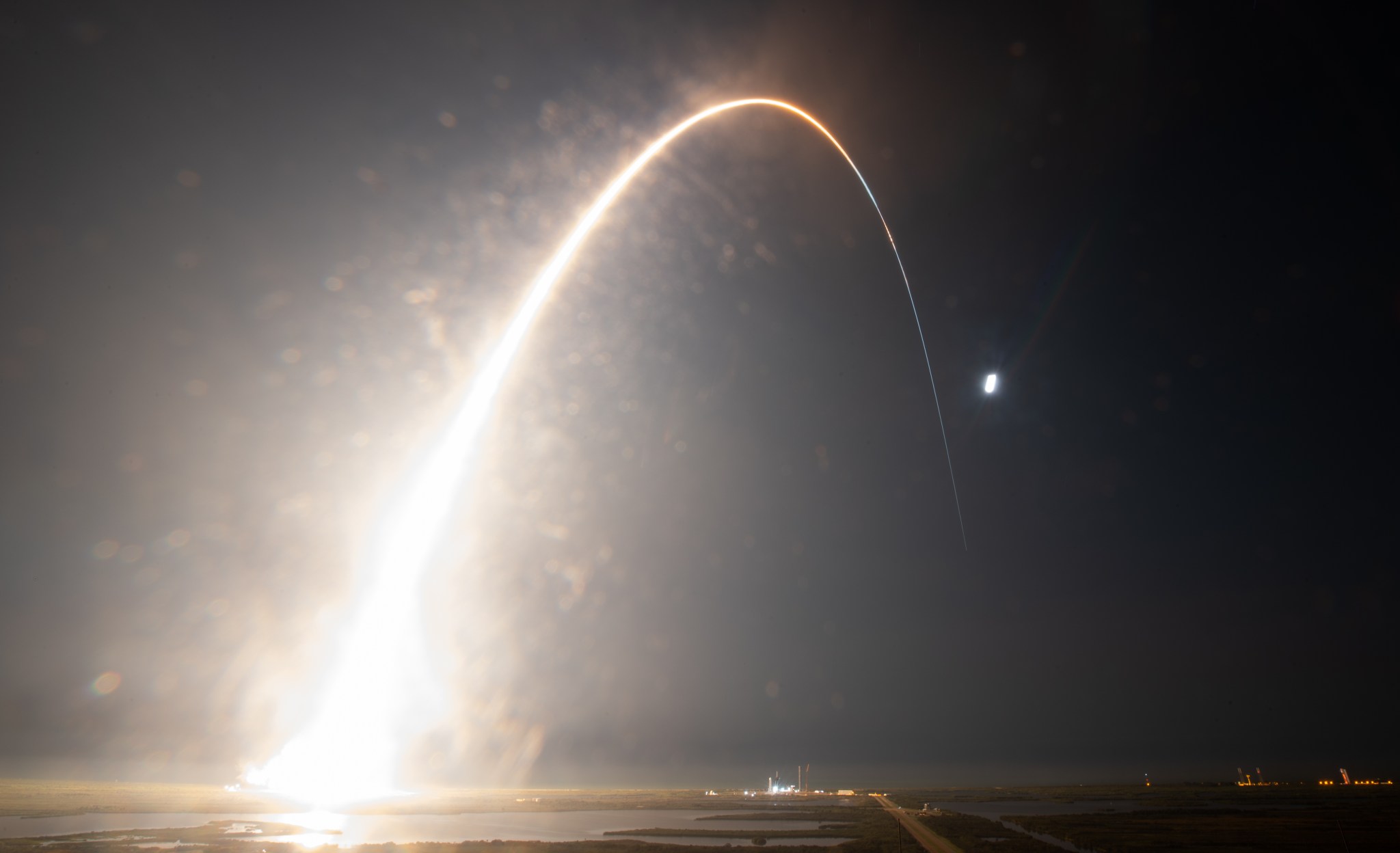 A five-minute exposure of launch and ascent appears as a bright, curving streak against the night sky.