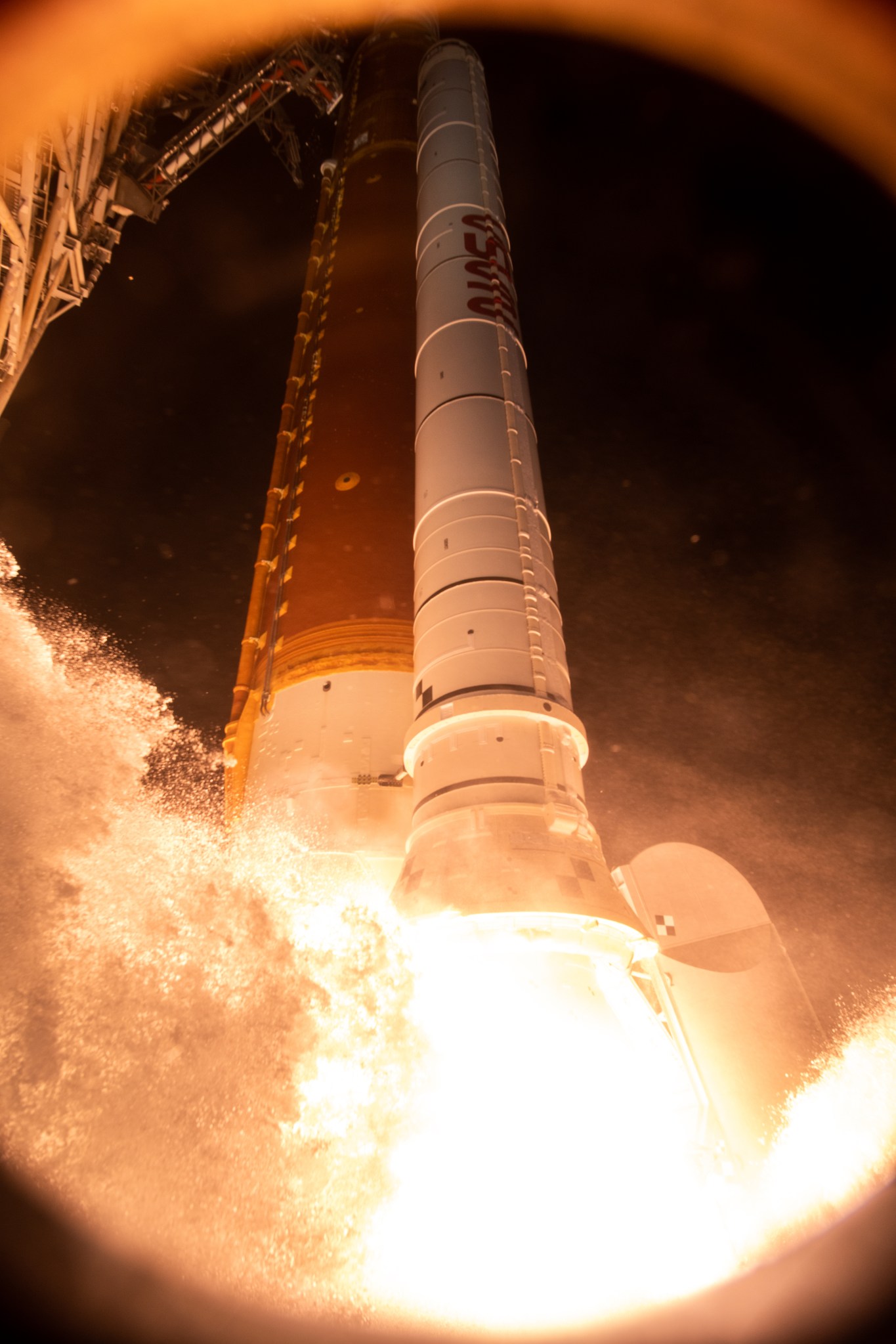 A bird's eye view of launch shows a brightly lit booster shortly after ignition. 