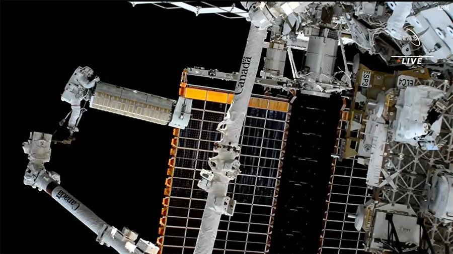 NASA spacewalker Josh Cassada rides the Canadarm2 robotic arm carrying the roll-out solar array to its installation site on the Starboard-4 truss segment. Credit: NASA TV