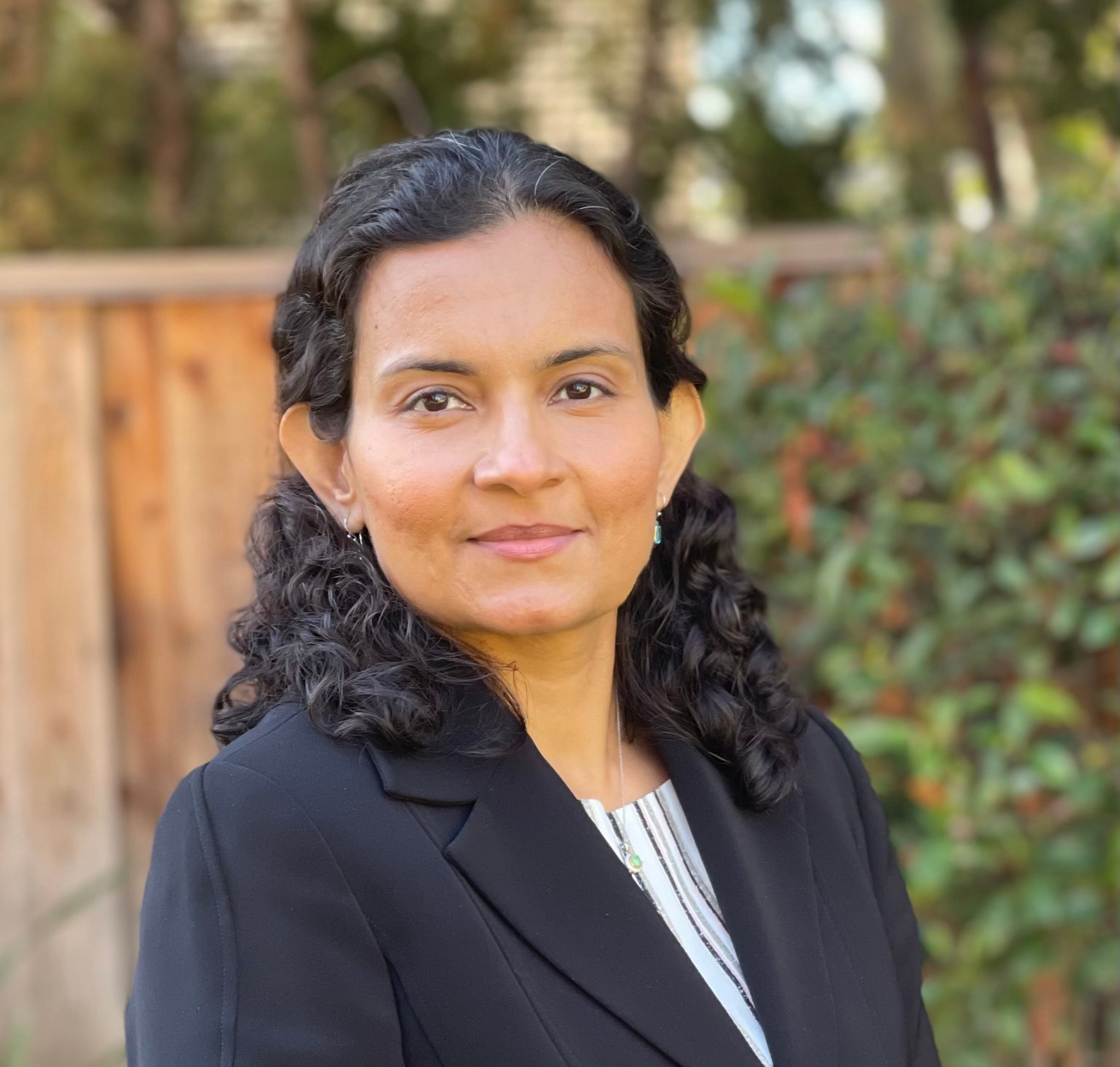 Portrait of Divya Bhadoria wearing a navy blue suit jacket. She is the second in command for NASA's Advanced Air Mobility national campaign.