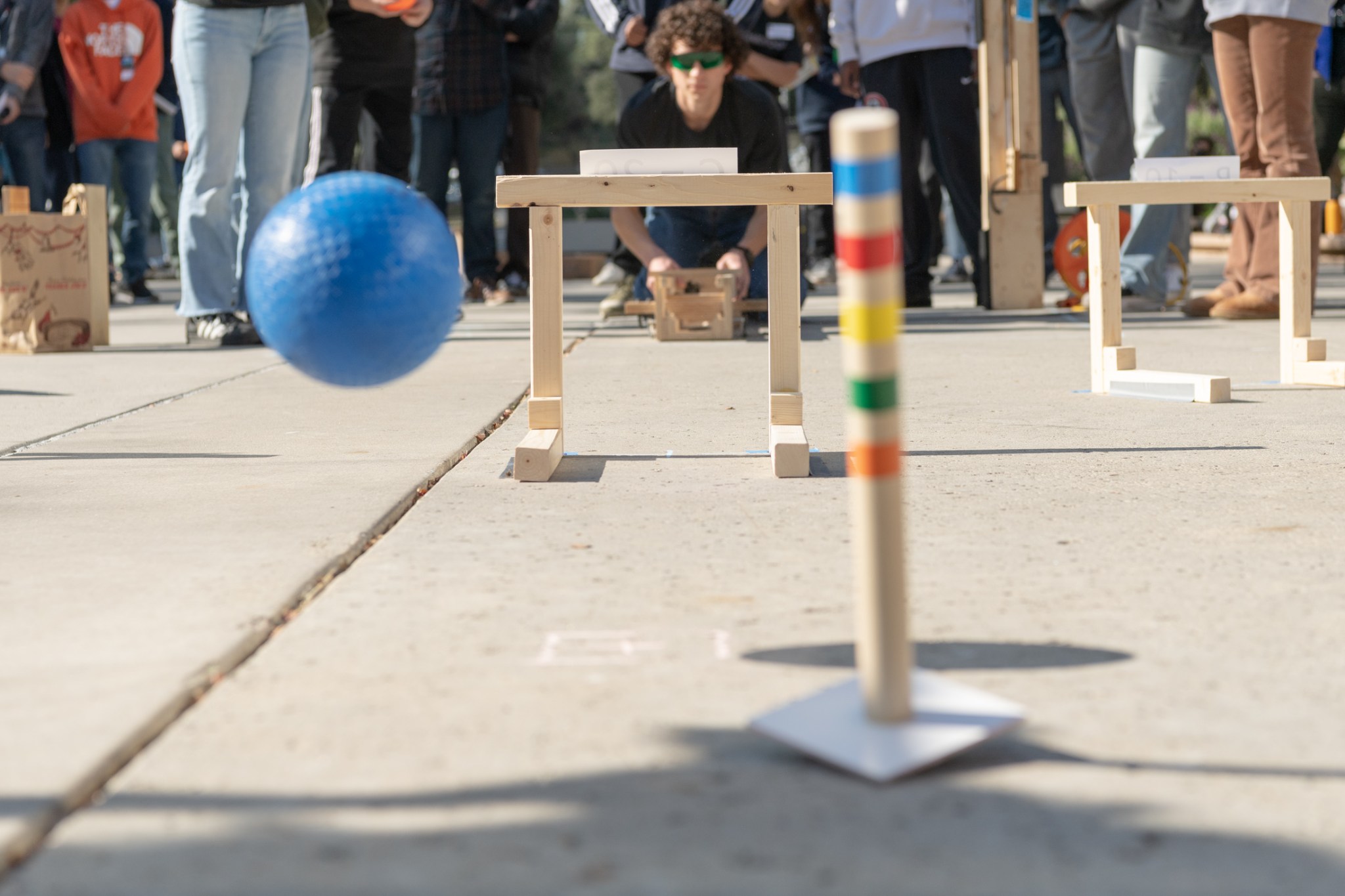 A student uses his team’s homemade device to shoot a ball through a wicket at JPL’s Invention Challenge.