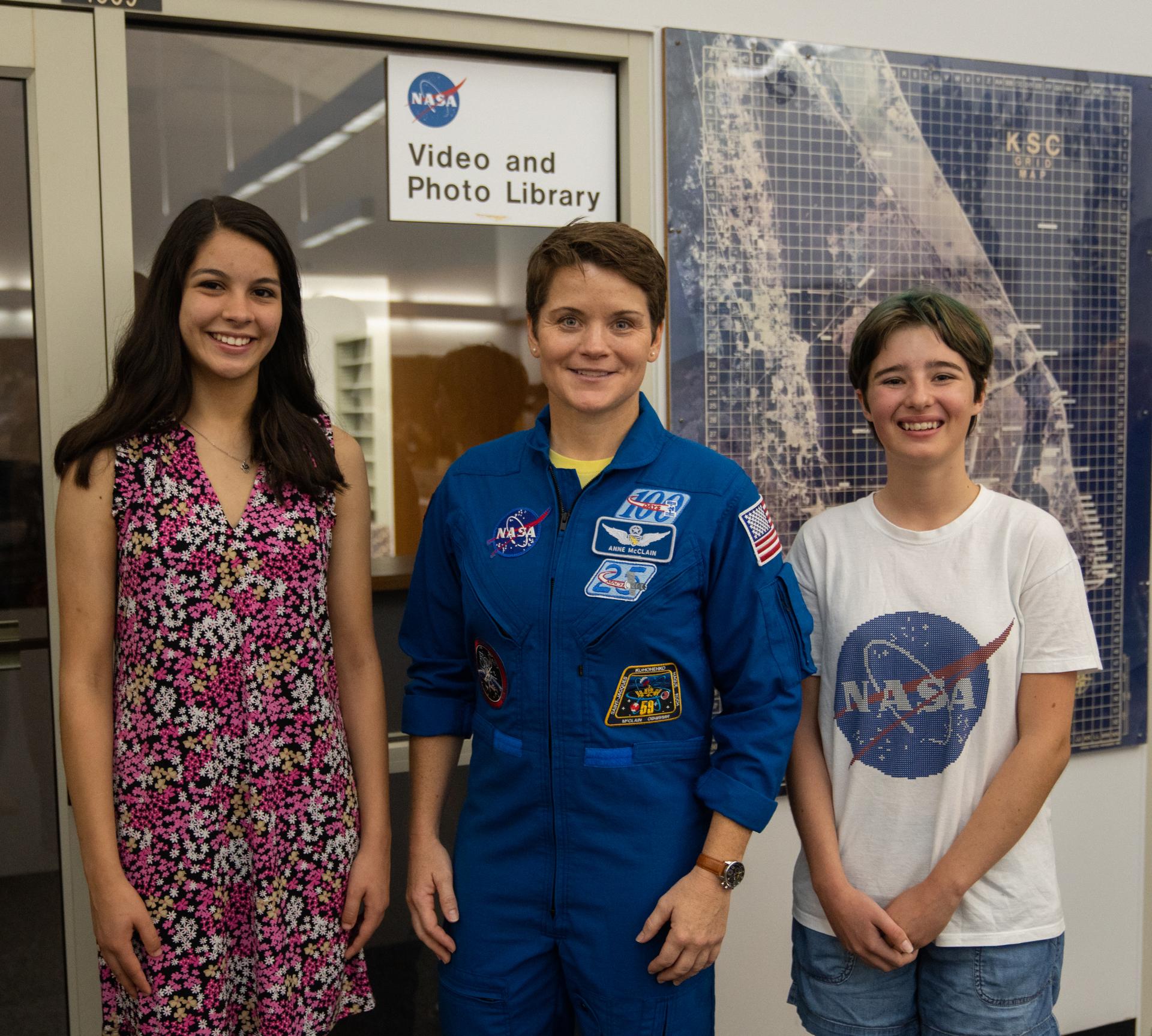 Student essay winners Amanda Gutierrez, left, and Taia Saurer pose with NASA astronaut Anne McClain