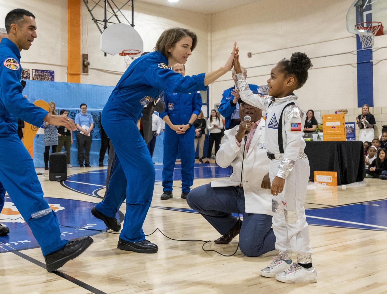 NASA astronaut Kayla Barron high-fives a student dressed in a spacesuit costume during a visit to Amidon-Bowen Elementary School in Washington D.C.