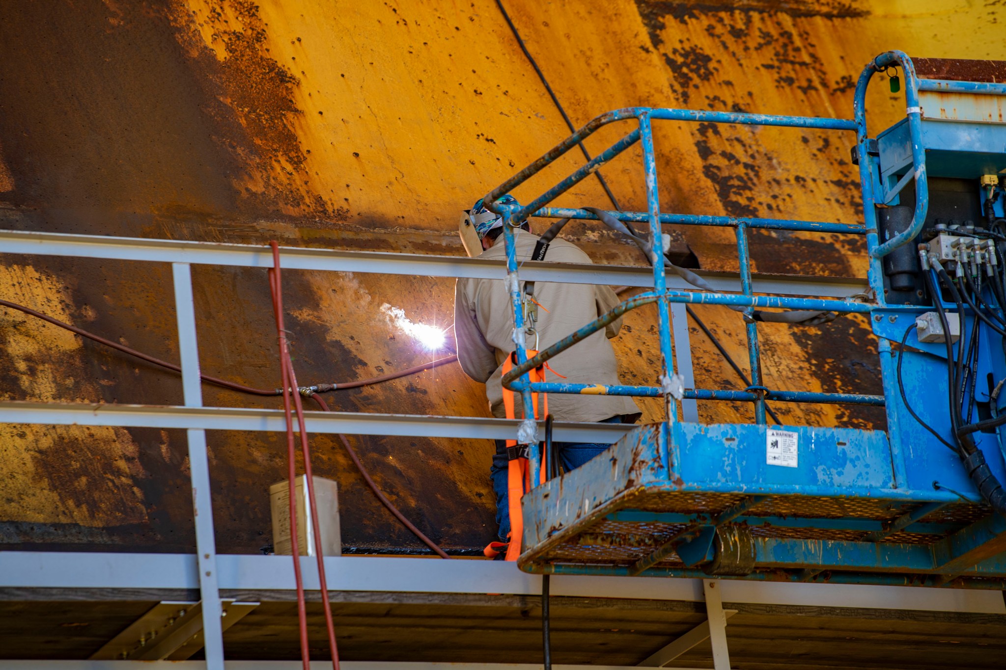 A welder works on modifications to the flame deflector on the Fred Haise Test Stand 