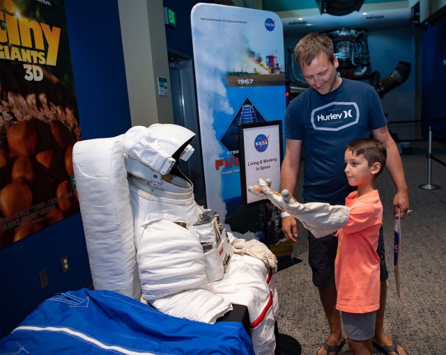 A young visitor tries out the astronaut glove exhibit at INFINITY Science Center.