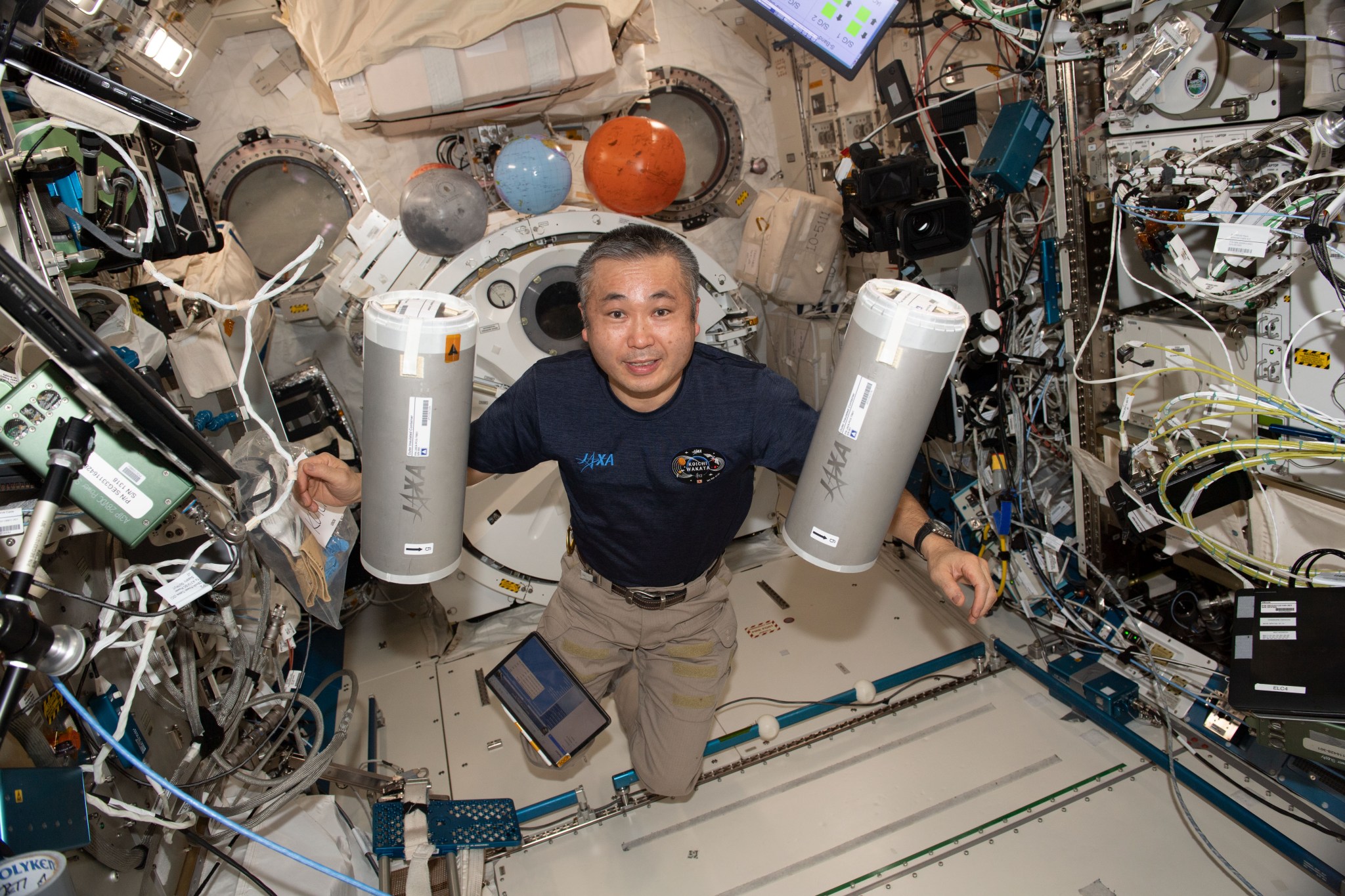 image of an astronaut holding containers storing experiment samples