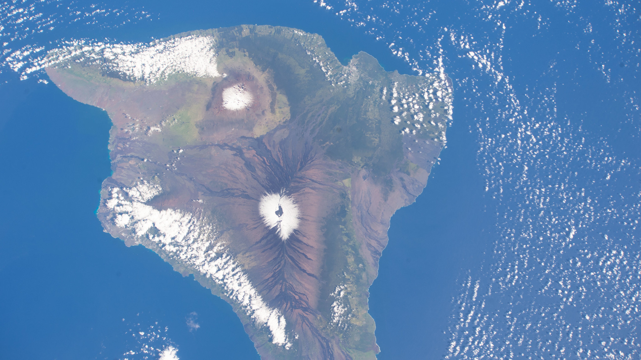 image of the snow-capped peaks of active volcano Mauna Loa, bottom, and dormant volcano Mauna Kea, top, on the island of Hawaii are pictured from the station
