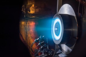 Hall thruster testing in a dark shot showing blue light from the thruster.