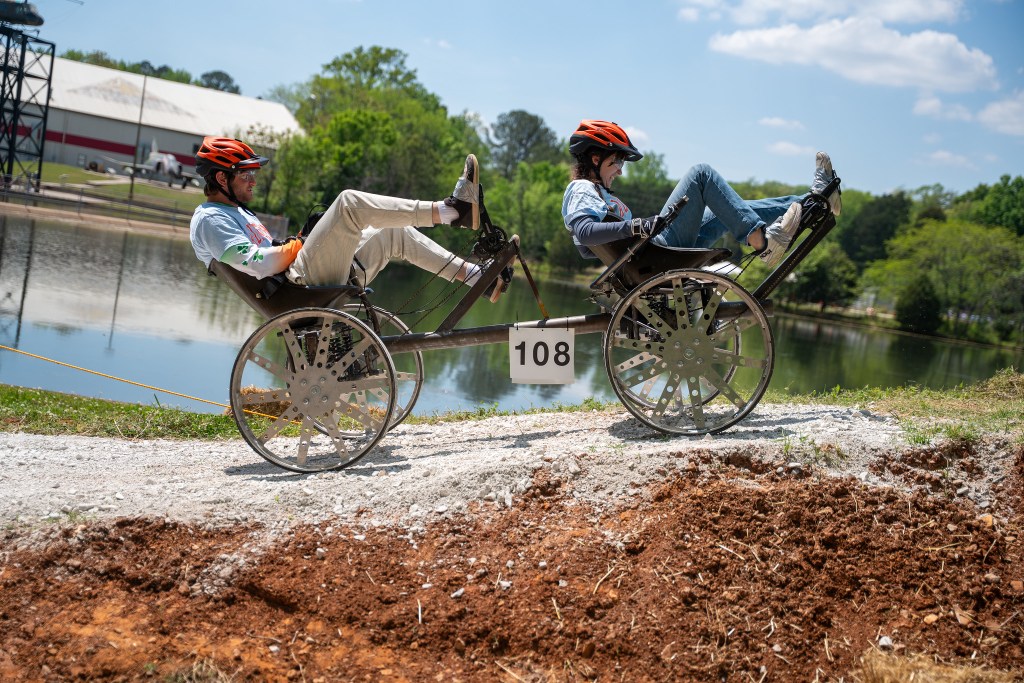 Two students in a hand-built rover make their way up a slope during the 2026 HERC Challenge