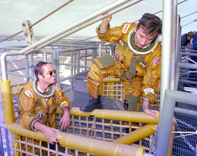 Astronauts Bob Crippen, left, and John Young board the emergency pad escape system known as the "slidewire" on Jan. 6, 1981.