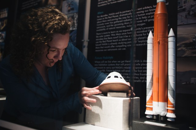 A NASA Archivist works with a miniature model of the Orion capsule for an exhibition about the Artemis Program