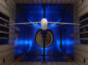 A scale model of truss-braced wing aircraft is suspended within a wind tunnel for testing.