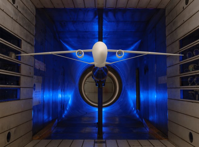 A scale model of truss-braced wing aircraft is suspended within a wind tunnel for testing.