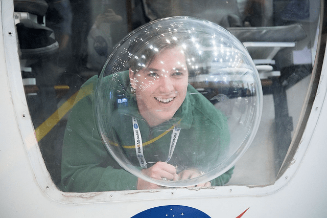 Person smiling and looking through a plastic globe window.