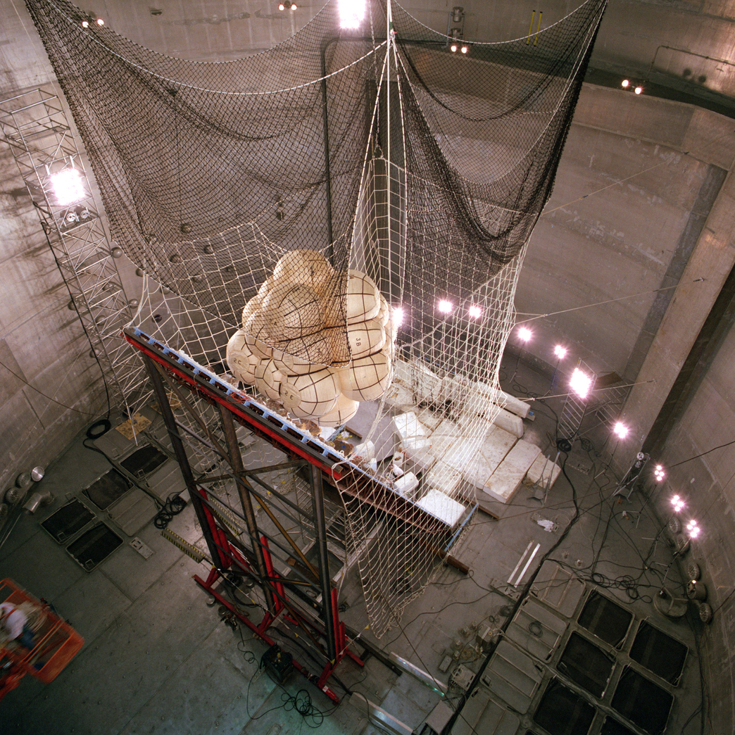 A cluster of airbags appear inside the netting of a drop apparatus inside a huge vacuum chamber.