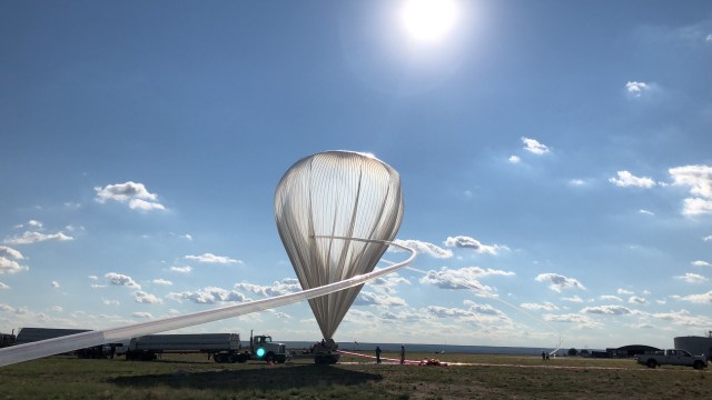 Scientific balloon, which is a clear, upside down teardrop shade, with a long tube leading to it being used to inflate it.
