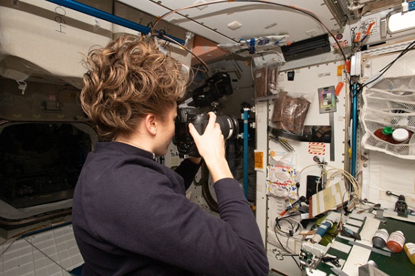 image of an astronaut taking pictures of a work area in the space station
