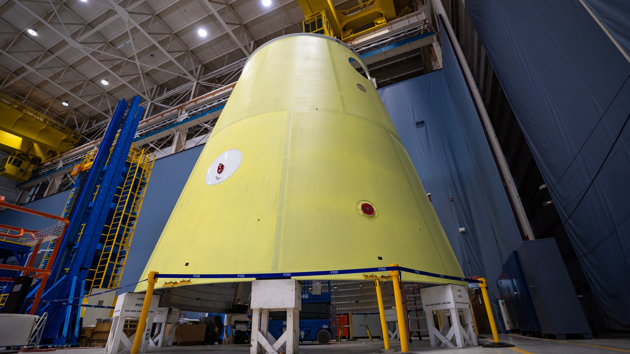 A yellow cone like structure in a warehouse sitting on top of stands 