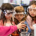 Four young students with safety glasses on working on an experiment