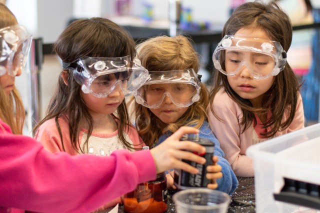 Four young students with safety glasses on working on an experiment