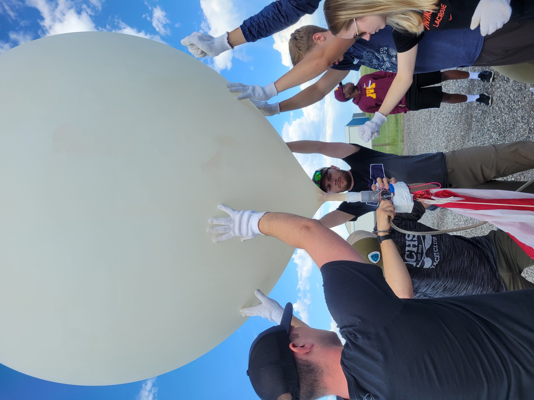 Students setting up a large white weather balloon