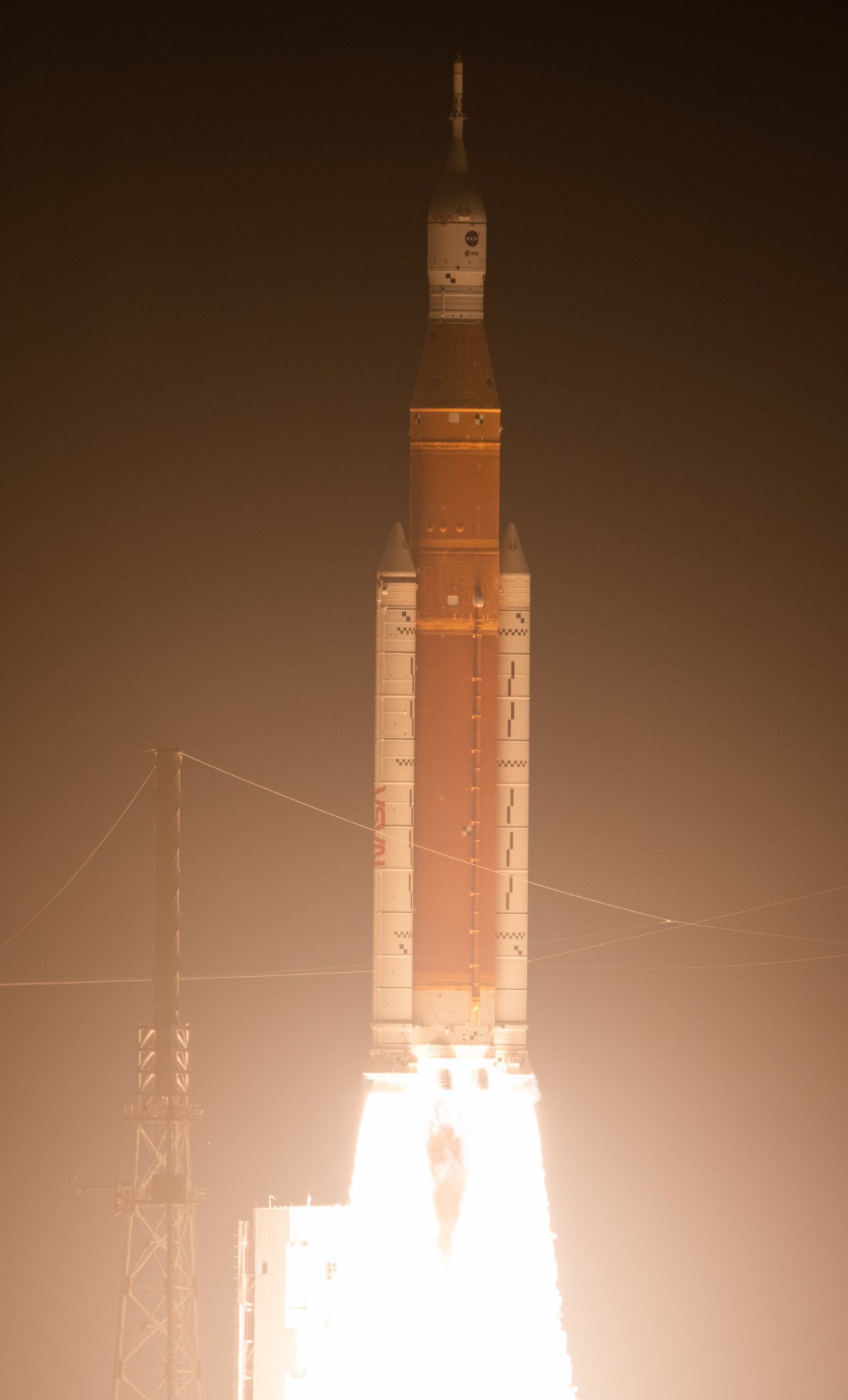 Artemis I launching from the launch platform, with a very large flame coming from the bottom of the rocket