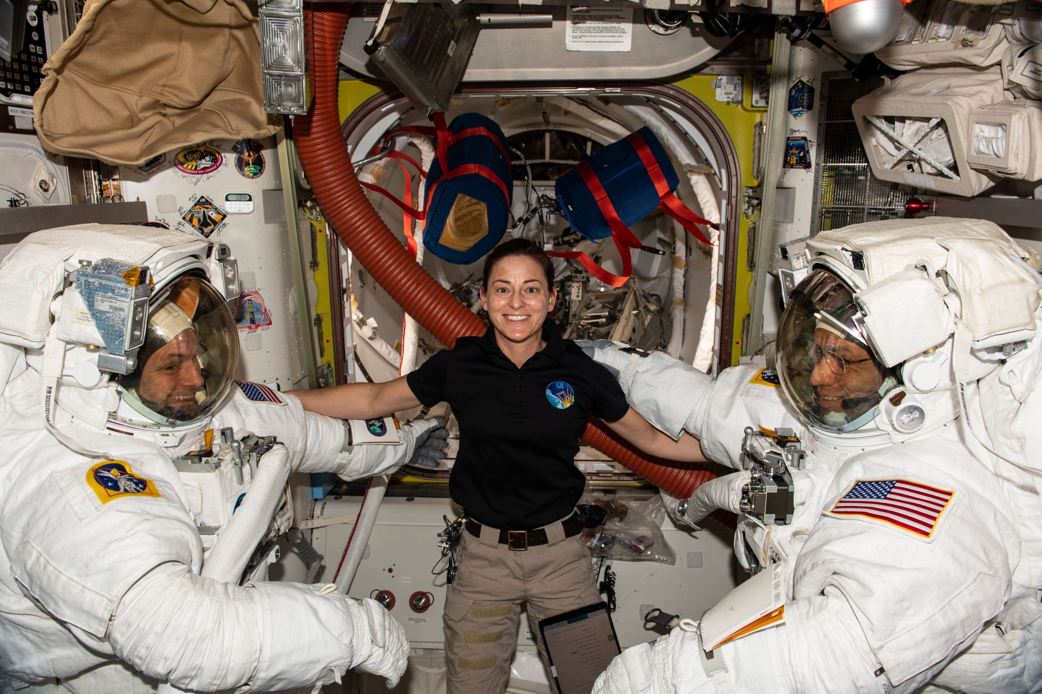 (Dec. 21, 2022) u002du002d- NASA Expedition 68 Flight Engineer Nicole Mann helps NASA spacewalkers Josh Cassada, left, and Frank Rubio, suit up for a spacewalk to install a roll-out solar array on the International Space Station.