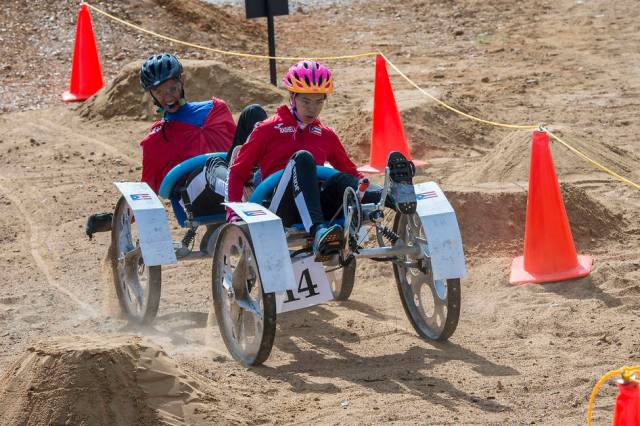 Two students travel over bumpy terrain in man-made rover