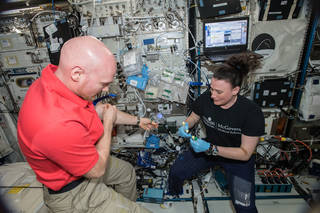 imagen de una astronauta realizando una extracción de muestras de sangre de otro astronauta para una investigación 