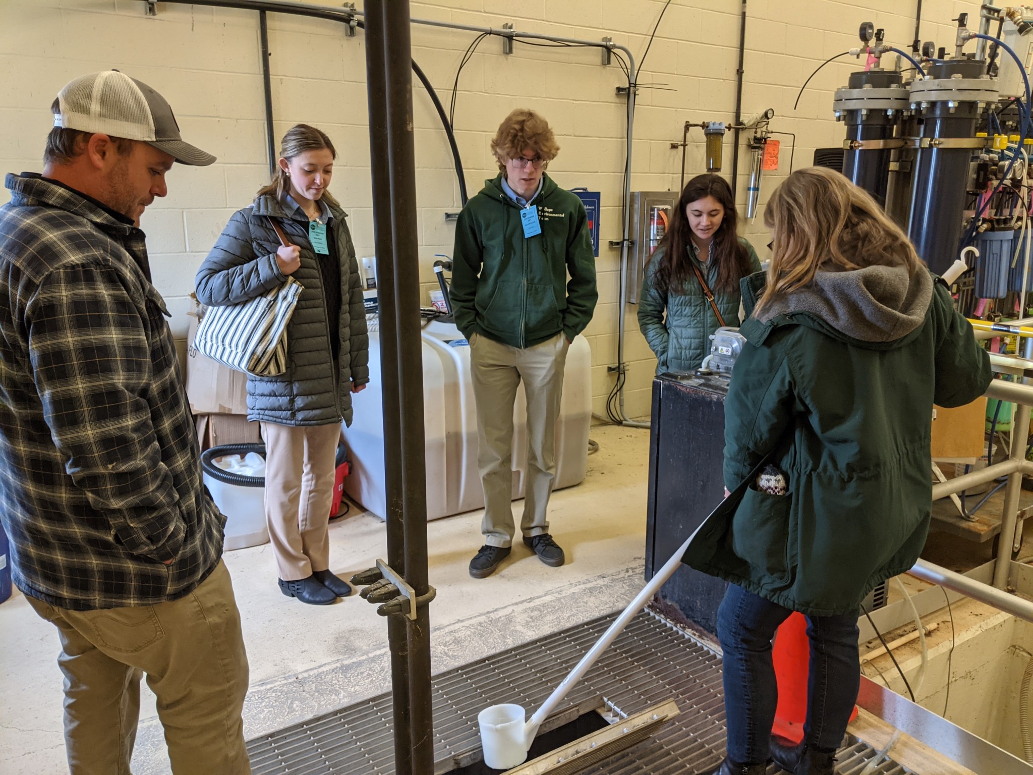Students watch a woman perform water sample testing.