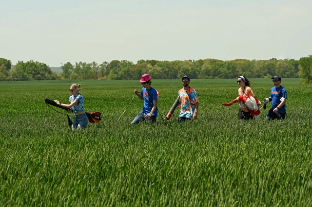 Student Launch participants retrieve their rocket from a field after launch.