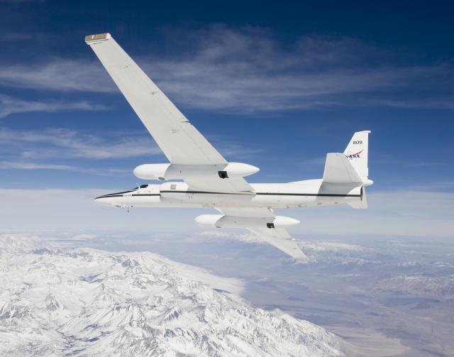 ER-2 high-altitude Earth science aircraft in flight over snowy mountains. 