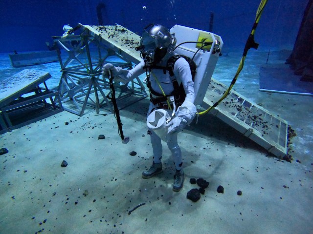Diver testing out an instrument under water, picking up rocks