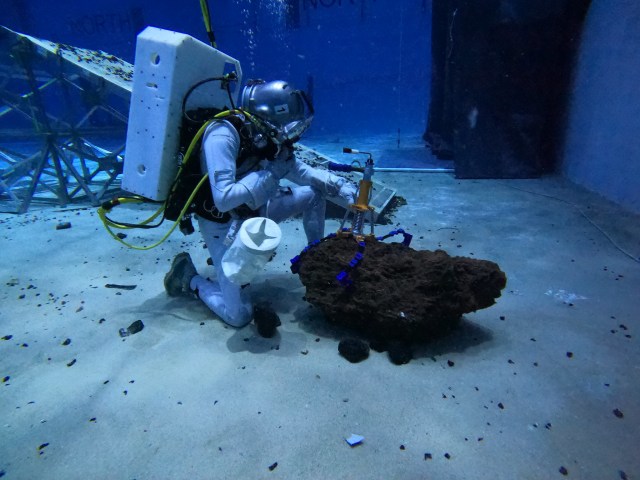 Diver tests out an instrument on a rock under water