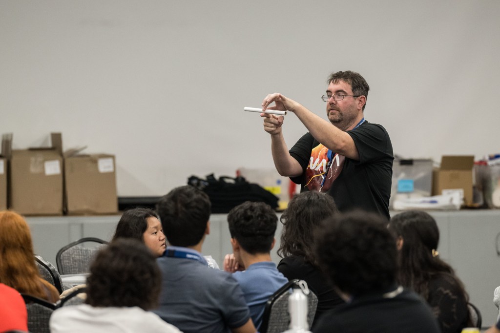 A counselor stands in front of a group of students at an onsite event for Texas Aerospace Scholars