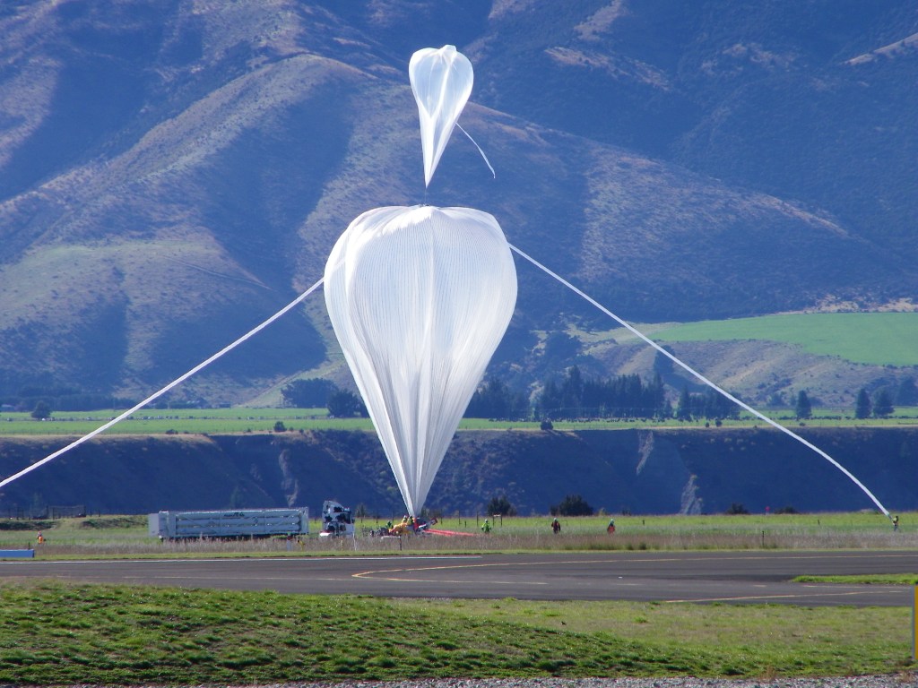 double zero pressure balloon inflation in front of new zealand mountains.