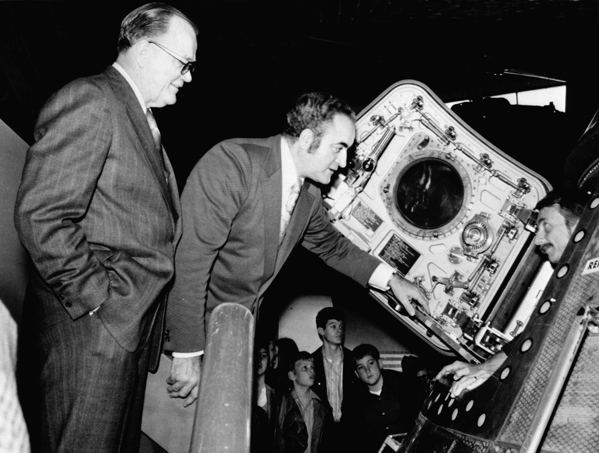 Rocco Petrone looks into an Apollo Command Module to talk to astronaut Owen Garriott