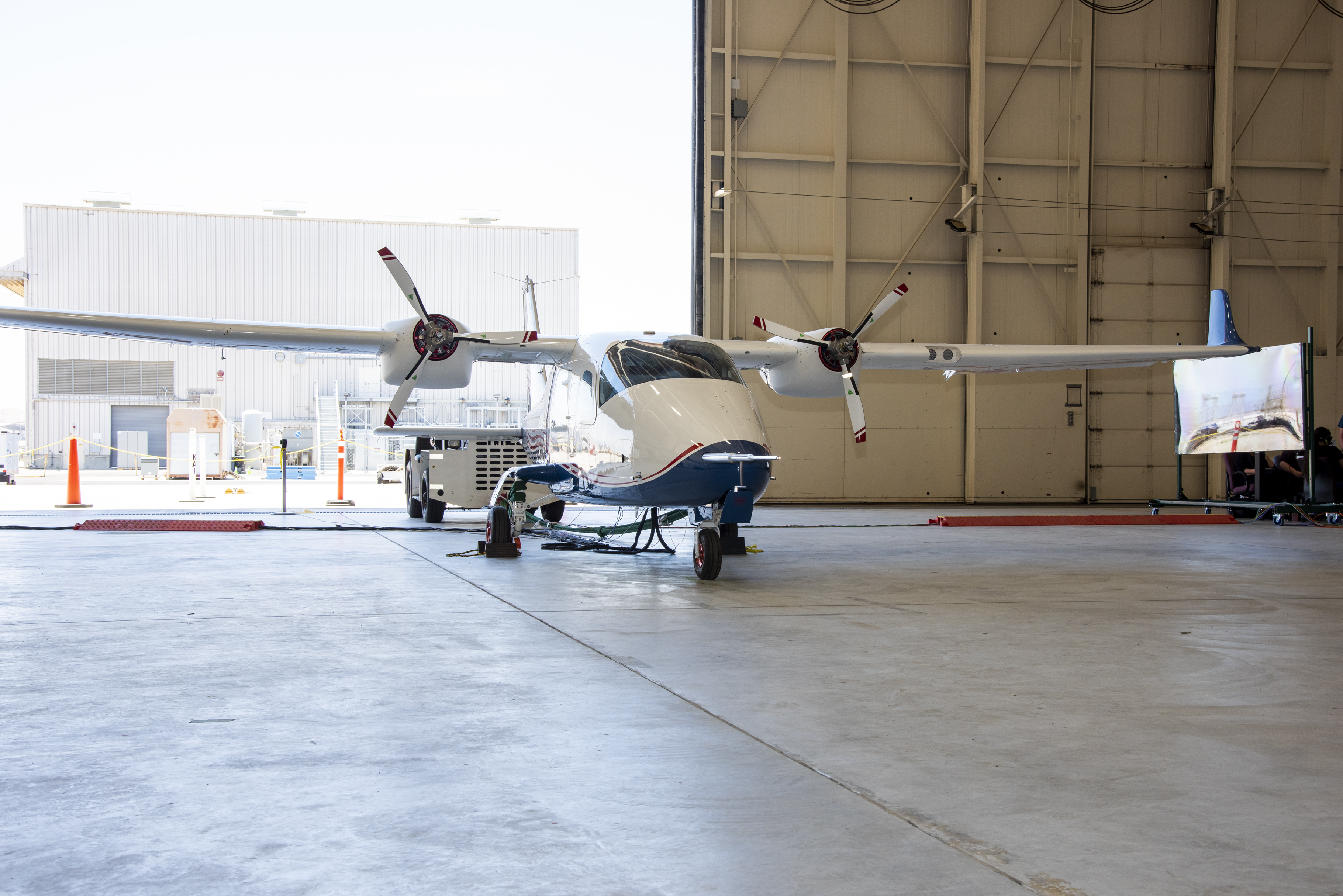 The X-57 aircraft inside a hangar with the hangar door open.