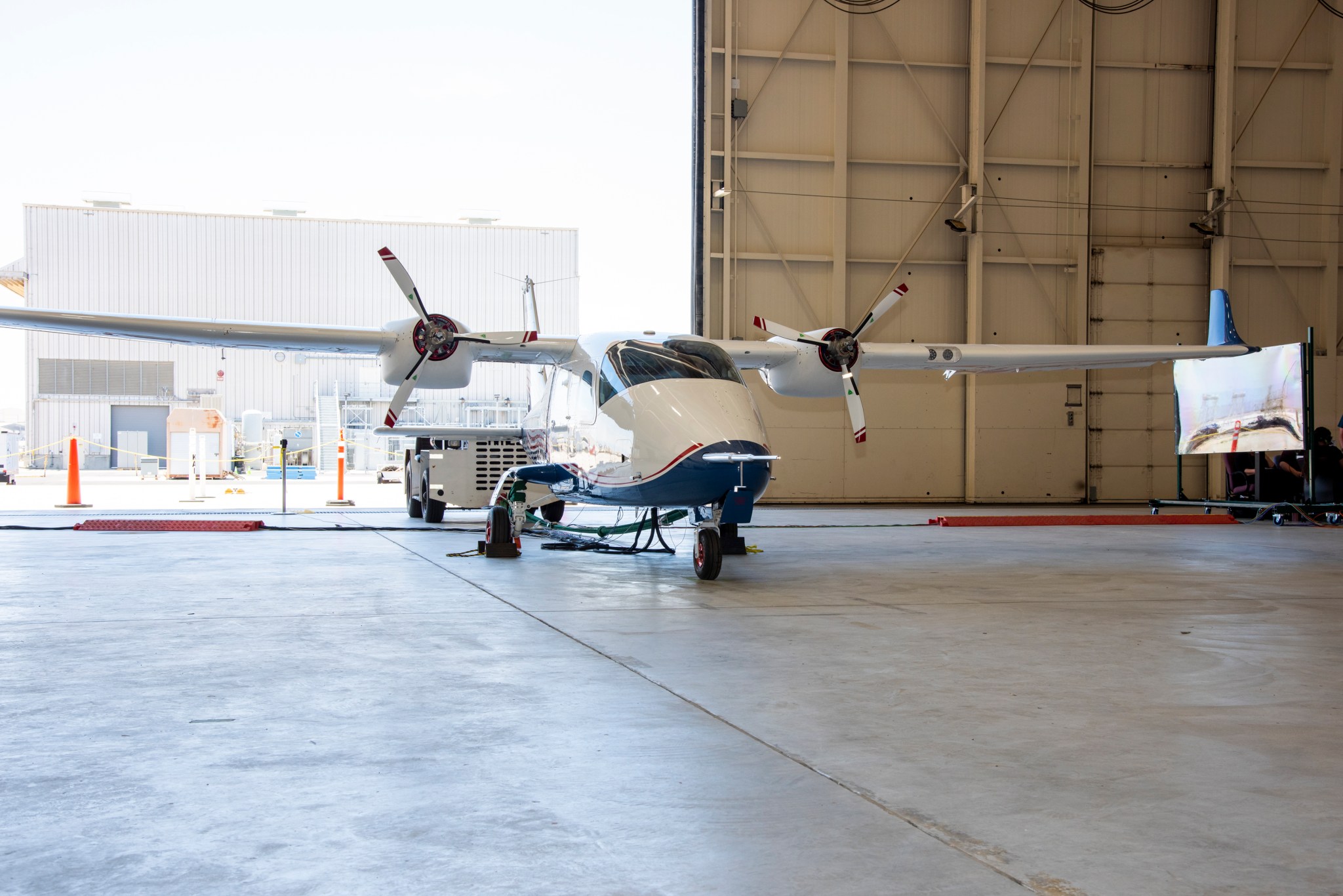 The X-57 aircraft inside a hangar with the hangar door open.