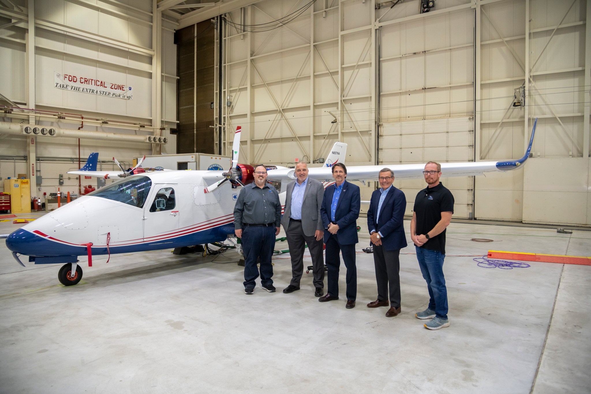 Five NASA personnel stand next to NASA aircraft.