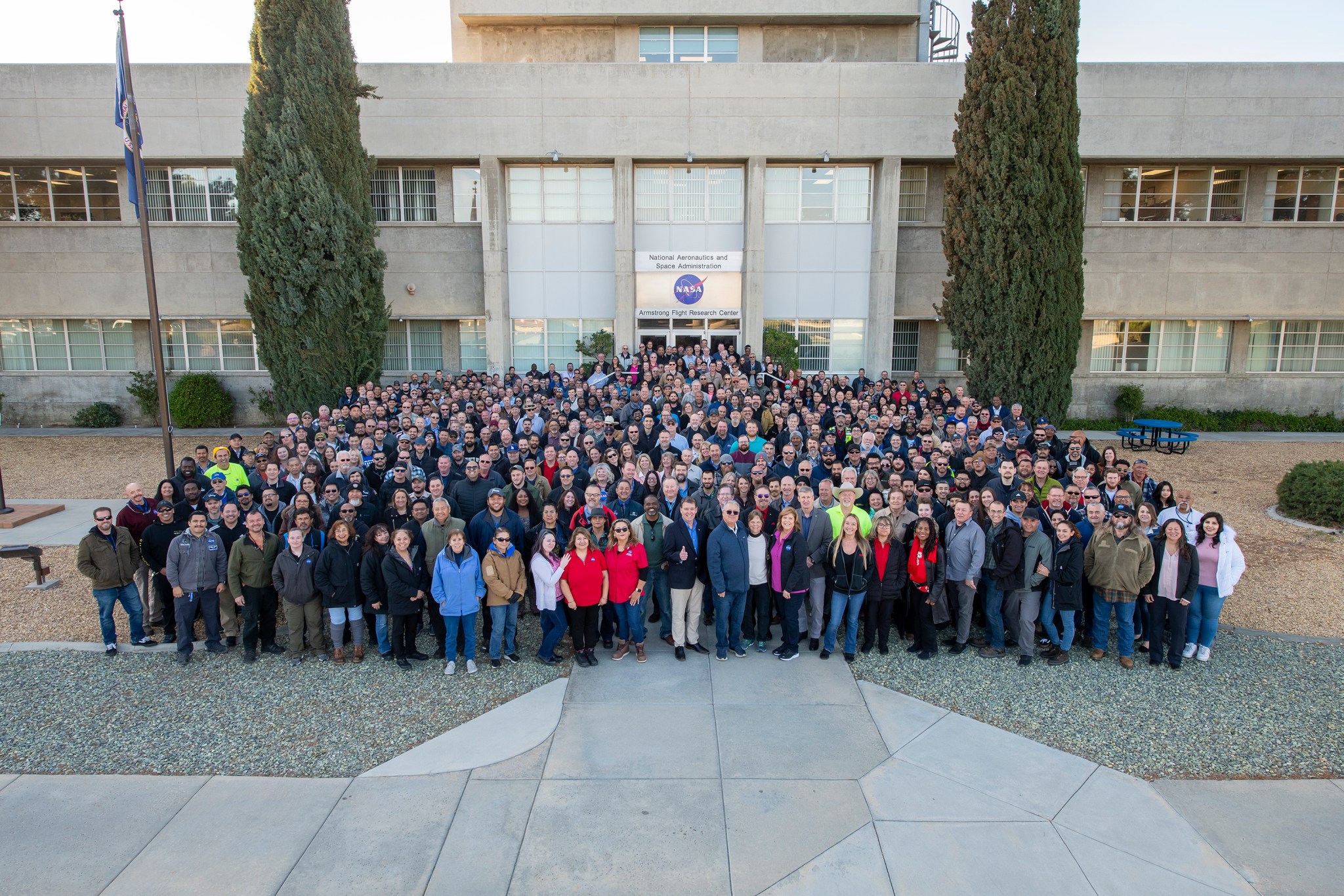 Large group of NASA Armstrong employees standing in front of NASA's Armstrong Flight Research Center's main building.