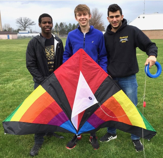 Photo of three boys standing in a field with a colorful kite