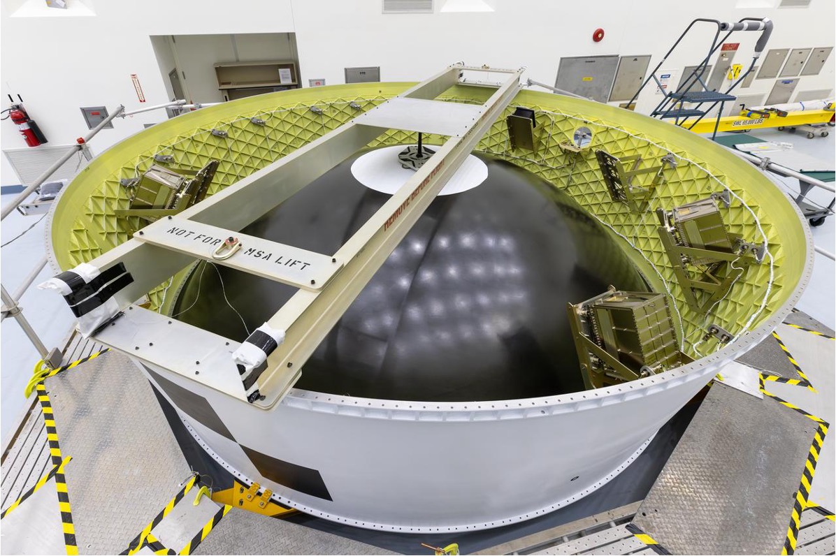 A giant metal dish with a black semi-sphere in the center of it and a ladder across it