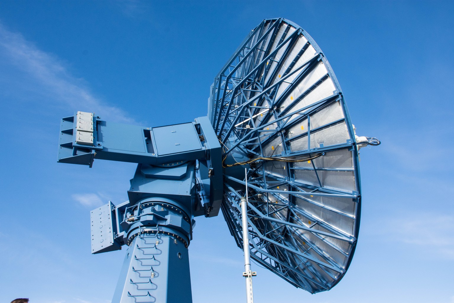 A blue antenna faces to the right with a bright blue sky behind it.