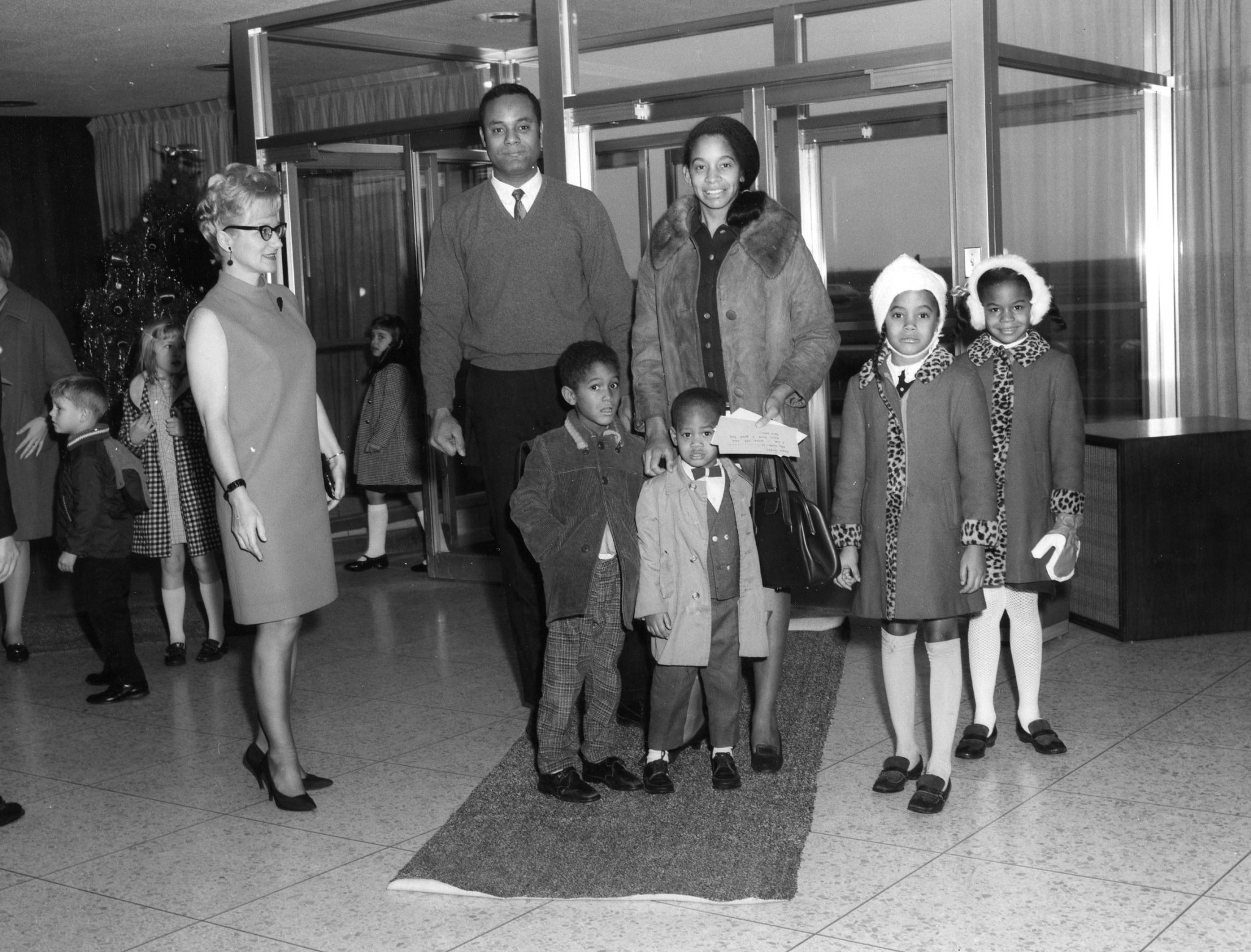 Father, mother, and four children stand in building lobby