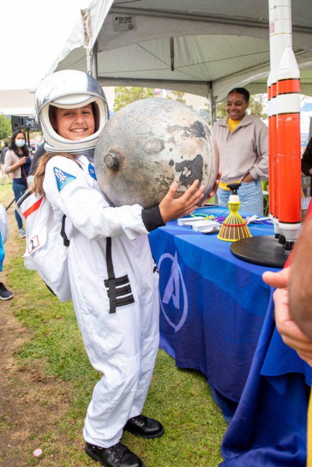 Young girl in an astronaut costume smiles as she holds a