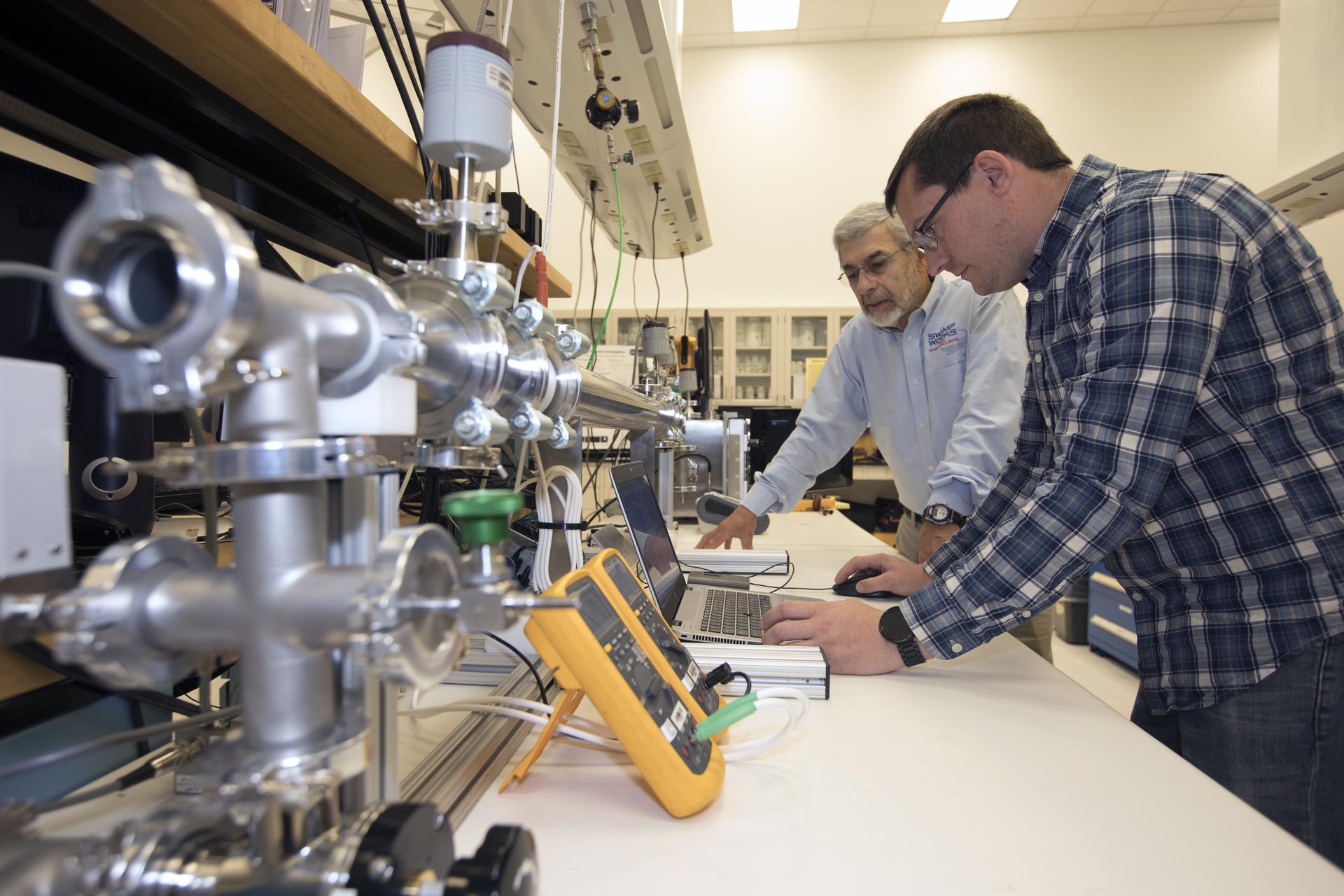 Scientist and a research physicist are modifying an electrostatic precipitator to remove dust from simulated Martian atmosphere.