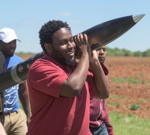 Student Launch participant carries rocket with smile on his face.